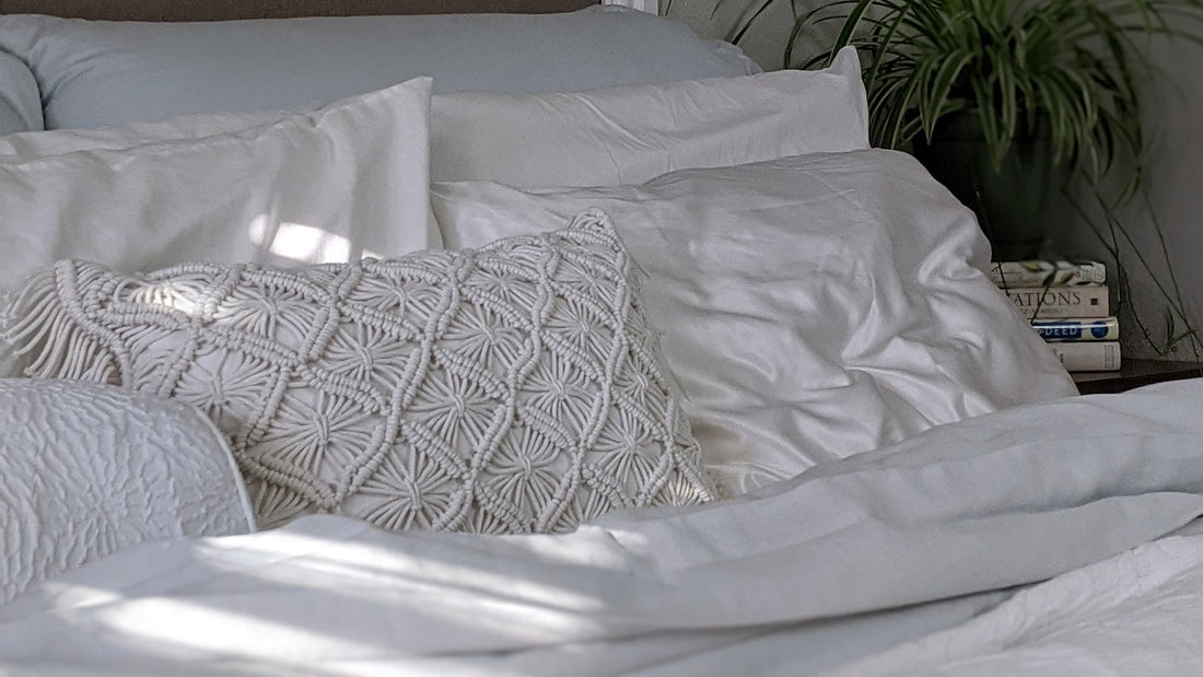 Ordentlich gemachtes Bett mit weisser und rosa Bettwaesche, helles Schlafzimmer